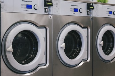 Row of Wascomat front-loading commercial washers with blue digital displays at Fresh Fold