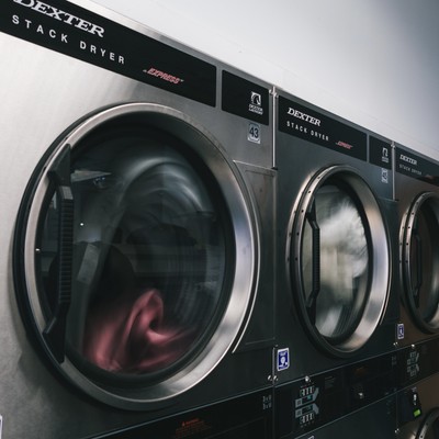 Row of Dexter stack dryers with laundry spinning inside at Fresh Fold