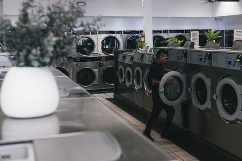 Fresh Fold team member loading a commercial Wascomat washer inside the laundromat