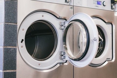Two adjacent commercial front-loading washers at Fresh Fold with doors swung open, showing empty stainless drums and door gaskets