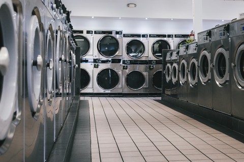 Rows of large-capacity Dexter stack dryers and Wascomat washers inside the Fresh Fold self-service area
