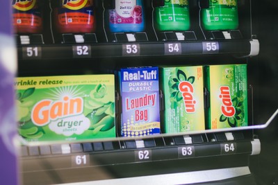 Vending machine lower shelf with Gain dryer sheets, laundry bags, and detergent at Fresh Fold