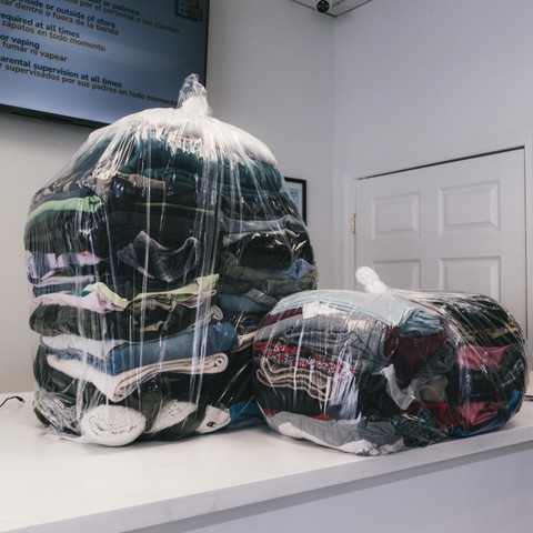 Neatly wrapped bags of clean laundry on the counter ready for customer pickup at Fresh Fold